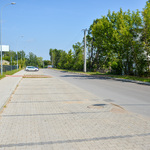 Asfaltowa ulica oraz jednostronny parking po lewej stronie.