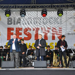 Prezydent Białegostoku oraz Proboszcz Parafii świętego Ojca Pio otwierają festyn. Na scenie za przemawiającymi siedzi orkiestra dęta.