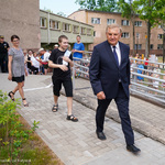 Zdjęcie terenu przed szkołą. Na pierwszym planie idący prezydent Białegostoku, za nim uczeń szkoły i dyrektorka. Za nimi stojący nauczyciele i uczniowie. W tle budynek szkoły.