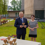 Teren otwarty przed szkołą. Na pierwszym planie stół do pingponga, na którym stoją statuetki w kształcie serc, za nim prezydent Białegostoku trzymający statuetkę i dyrektorka szkoły. W tle budynek szkoły.