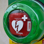 Duże zbliżenie na defibrylator AED zamontowany na ścianie.