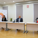 Trzy osoby siedzące za stołem konferencyjnym