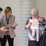 Cztery kobiety stoją obok siebie rozmawiając. Patrzą na kartki trzymane w dłoniach.