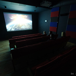 Pomieszczenie sali kinowej. Ciemność rozświetla jedynie duży, włączony ekran.  