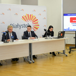 Prezydent miasta wraz z zastępcą, dyrektorką Centrum Aktywności Społecznej i rzeczniczką prasową Urzędu Miejskiego siedzą przy stole konferencyjnym ustawionym na tle logo miasta. 