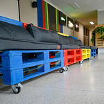 Kolorowe siedziska zrobione z pomalowanych palet magazynowych stoją na korytarzu szkolnym.
