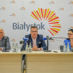 Uczestnicy konferencji siedzący za stołem. Zastępca prezydenta miasta mówi do mikrofonu.