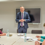 Jasne pomieszczenie, Zastępca Prezydenta stojąc mówi do członkiń i członków rady siedzących przy dużym stole. Za nim, na ścianie, wisi wyłączony ekran multimedialny.