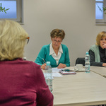 Uczestniczki posiedzenia siedzą przy stole. Jedna z kobiet robi notatki. 