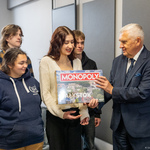 Konferencja prasowa w szkolnej strefie relaksu. Prezydent Białegostoku wręcza uczniom grę planszową.