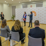 Dyrektorka Centrum Aktywności Społecznej mówi do mikrofonu, uczestnicy konferencji siedzą na krzesłach.