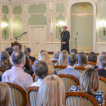Prawosławny duchowny mówi przez mikrofon do osób uczestniczących w gali.