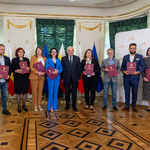 Bogato zdobione wnętrze Pałacyku Gościnnego. Wszyscy członkowie nowopowołanej Rady i prezydent Białegostoku pozują do zdjęcia na tle ścianki z logo Miasta Białystok.